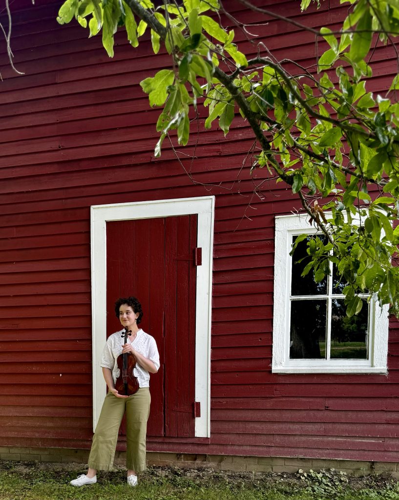 Girl with violin in front of barn